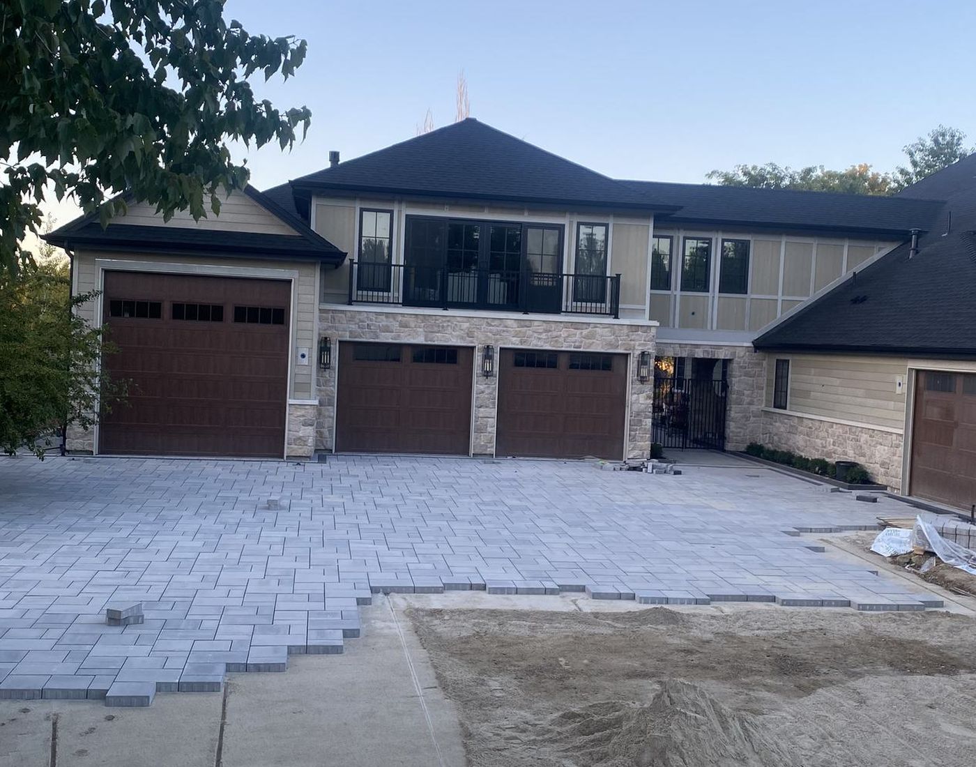 The same driveway mid-installation, with pavers part-laid and bedding sand still exposed.