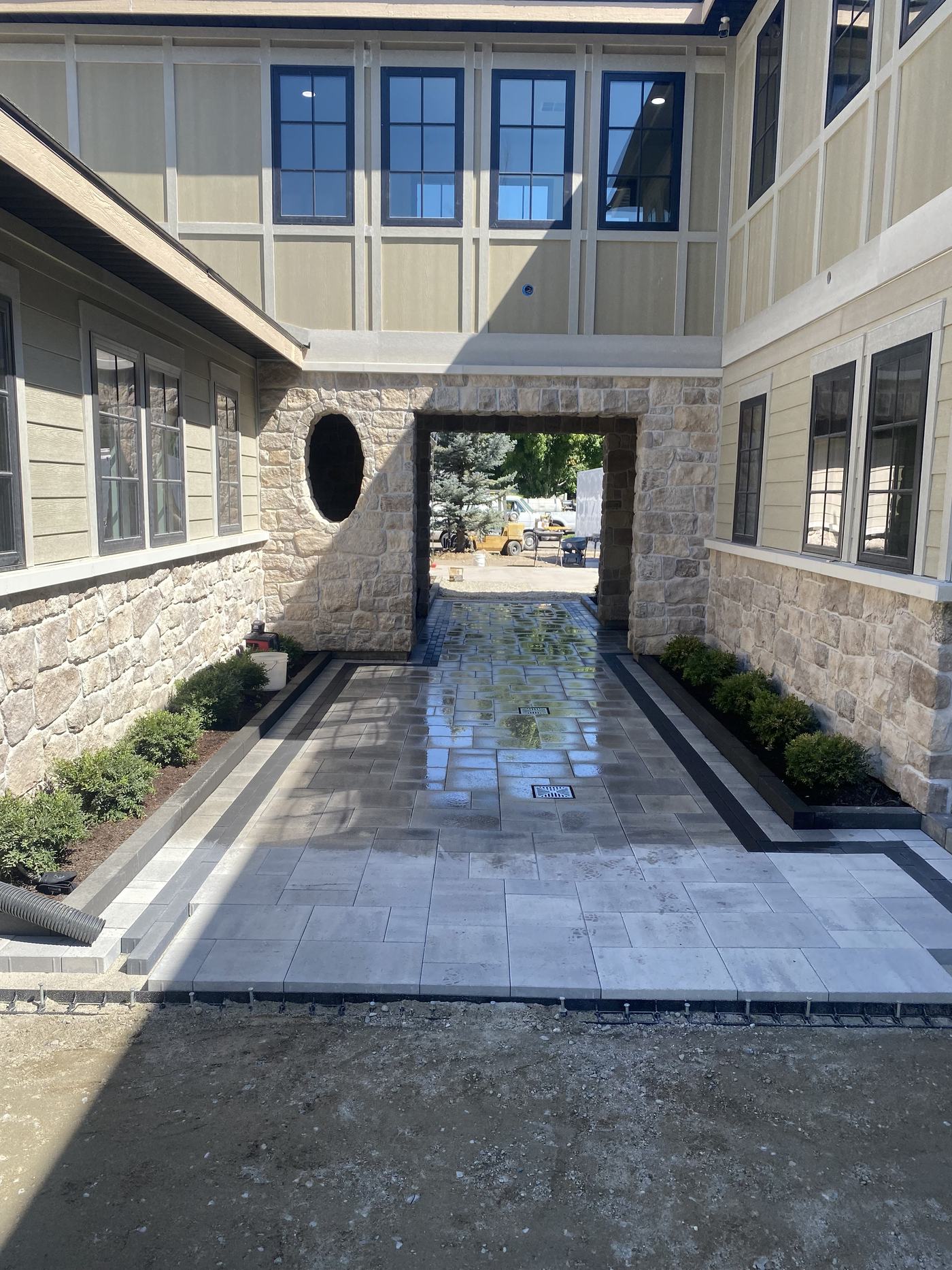 A narrow stone courtyard with a linear water runnel running its length, flanked by clipped evergreens.