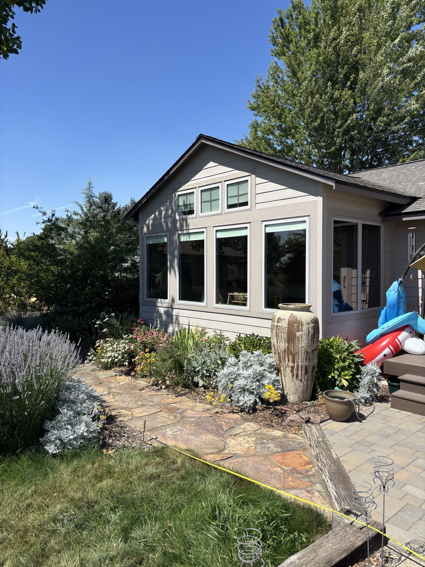 A front entry garden with lavender, silver foliage and a tall ceramic urn fountain beside a flagstone landing.