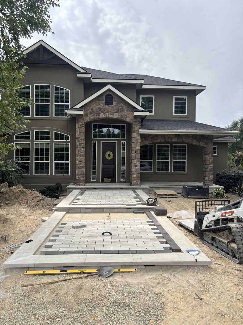 The front elevation of a stone-and-stucco house with arched windows and a wreath on the door.